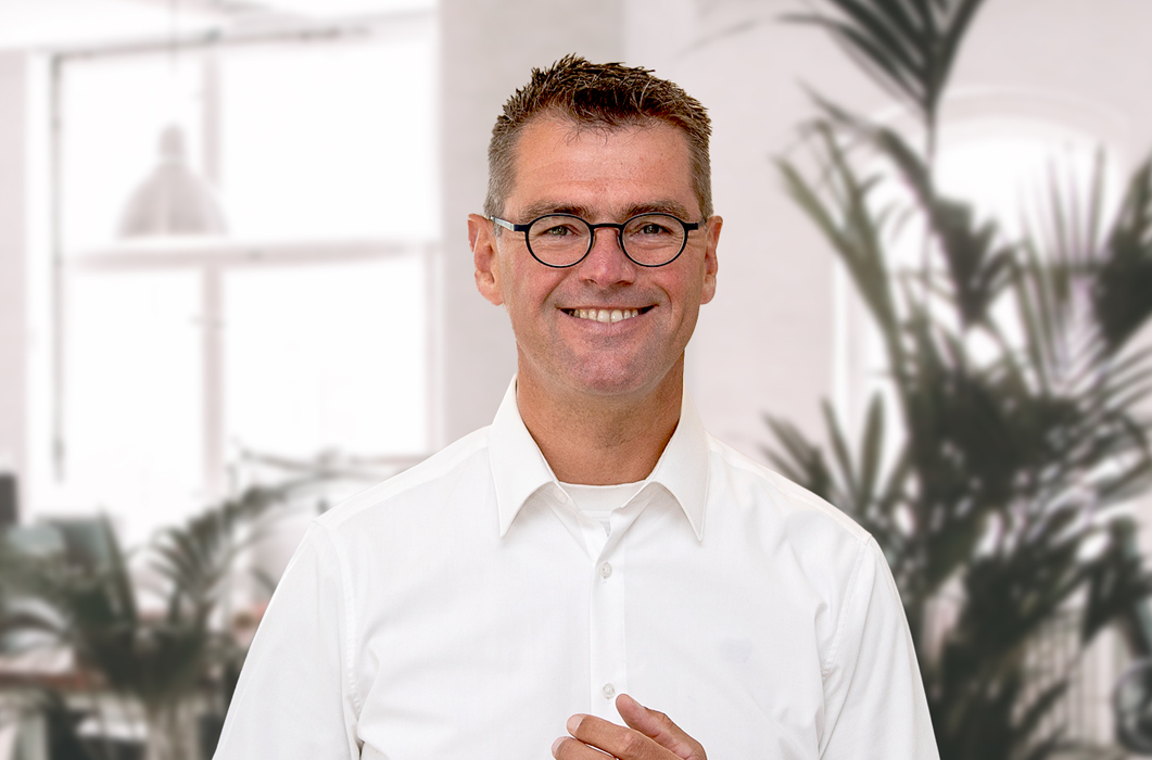 Immobilienmakler Christian Heeks im Büro mit Brille und weißem Hemd